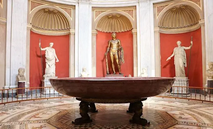 Classical statues in the Round Hall of the Pio Clementino Museum, around a large porphyry basin